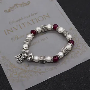 Dettaglio del bracciale di perle con ciondolo a cuore in argento vintage su invito di lusso