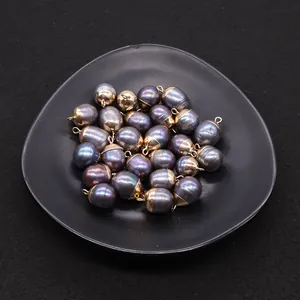 Dettaglio di perle barocche nere naturali con riflessi viola e anellini dorati