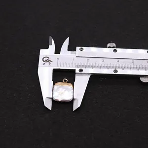 Dettaglio della misurazione di 1,5 cm di un ciondolo di perla barocca quadrata con un calibro