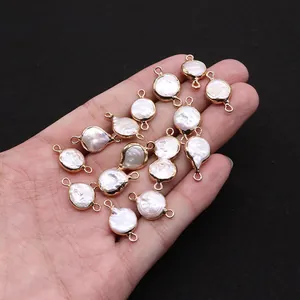 Detail of round flat shell charms with gold edges held in hand for size reference