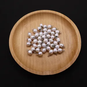 Macro view of natural freshwater oval pearls with silver metal bails in a wooden tray