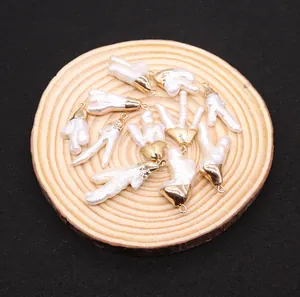 Makro-Detail von unregelmäßigen Barockperlen-Anhängern mit Goldkappen auf Holzscheibe