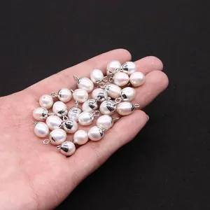 Macro shot of oval freshwater pearl pendants with silver connectors held in a hand
