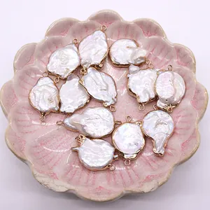 Pendentifs en perles d'eau douce baroques avec bords dorés sur un plateau floral rose