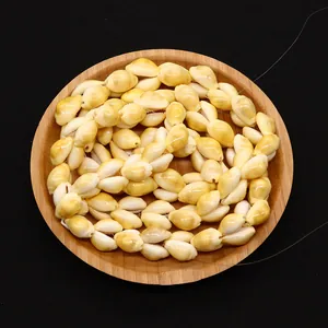 Close-up of natural white and yellow cowrie shell beads on a round wooden tray