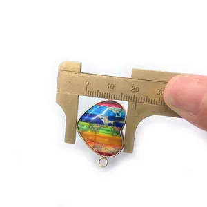 Macro shot showing a 20mm colorful heart-shaped stone pendant measured with a caliper