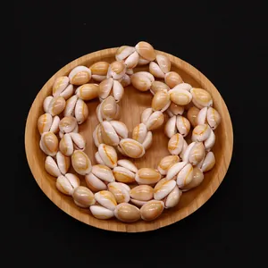 Detailed macro view of natural cowrie shell beads with yellow stripes in a wooden tray