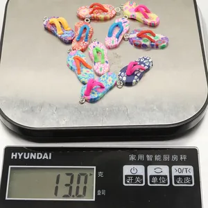 Detailed view of flip-flop shaped floral pendants weighing 13 grams on a digital scale