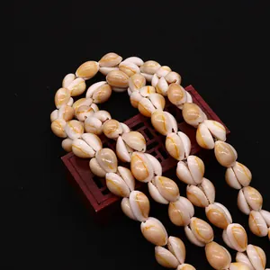 Macro shot of natural cowrie shell beads with yellow patterns on vintage wooden base