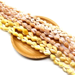 Natürliche Kauri-Muschelperlen in Weiß und Gelb auf Holztablett für DIY-Schmuckherstellung