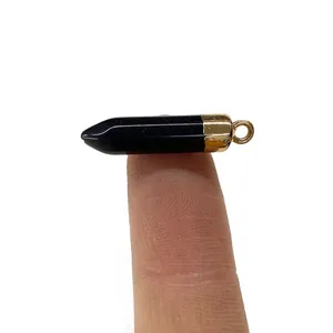 Schwarzer gefleckter Stein-Anhänger mit Goldkappe, auf dem Finger zur Größenreferenz