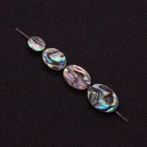 Détail macro de perles ovales en nacre d'abalone aux reflets irisés pour bijoux DIY
