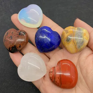 Close-up of polished heart-shaped natural gemstones held in hand for size reference