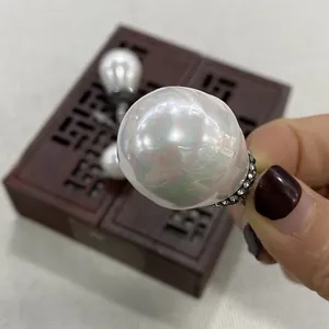 Pendentif goutte en perle baroque avec strass incrustés présenté dans une main