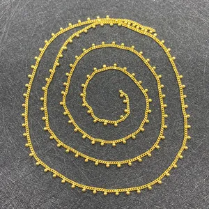 Macro detail of golden twist chain with 2mm beads for DIY jewelry making