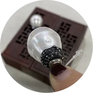 Pendentif en perle baroque serti de strass noirs présenté sur un fond en bois sombre
