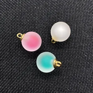 Dettaglio di pendenti a sfera in acrilico opaco rosa, bianco e blu con gancio dorato