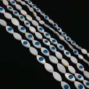 Macro shot of marquise shell beads with evil eye motif on a black background