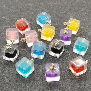 Dettaglio macro di ciondoli a cubo in acrilico multicolore con anelli dorati per DIY