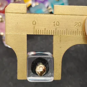 Macro di un pendente a cubo in acrilico da 10 mm con nucleo dorato durante la misura