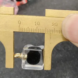 Macro di un ciondolo quadrato in acrilico da 12mm misurato con un calibro in ottone
