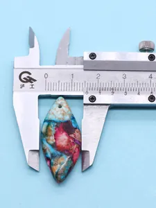 Measuring diamond turquoise stone pendant size with digital caliper on blue background