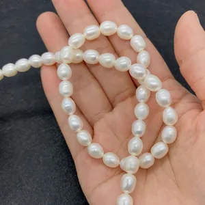 Macro shot of AAA grade white rice-shaped freshwater pearls held in hand for size reference