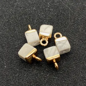 Macro shot of five cube-shaped imperial stone pendants with gold metal frames and natural texture
