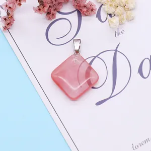 Close-up of a polished pink quartz diamond-shaped pendant with a silver metal clasp