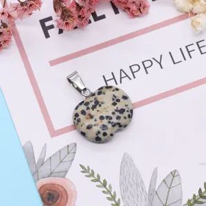 Close-up of apple-shaped Dalmatian Jasper stone pendant with silver metal bail on floral card