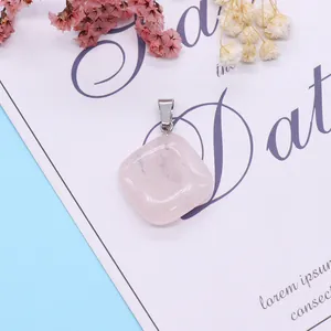 Polished cushion-cut pink quartz pendant with silver bail on decorative background