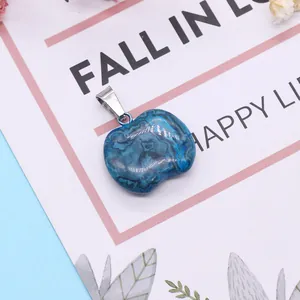 Apple-shaped natural blue stone pendant with marble texture and silver clasp on a card