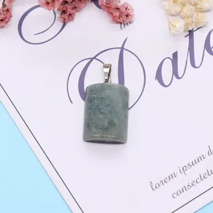 Macro shot of semi-cylindrical malachite stone pendant with silver clasp on white paper