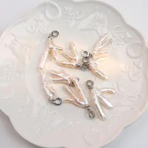 Macro shot of unique baroque pearl pendants with silver clasps on a white ceramic plate