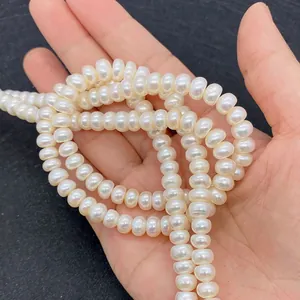Macro shot of high luster flat round natural freshwater pearls held in hand for scale