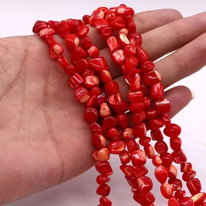 Primer plano de cuentas de concha rojas pulidas para joyería DIY sostenidas a mano
