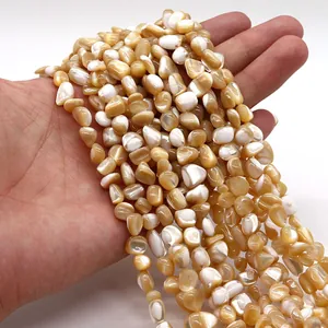 Cuentas de concha natural irregular con brillo nacarado sostenidas en la mano