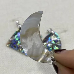 Gros plan détaillé de pendentifs en nacre en forme de lune et de triangle aux reflets irisés