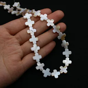 Vue détaillée de perles en nacre naturelle en forme de croix pour la création de bijoux