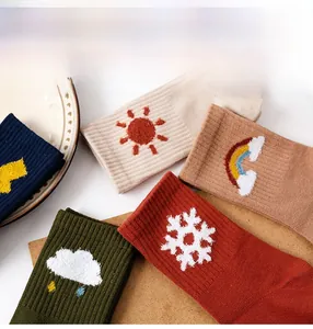 Detail of colorful combed cotton socks with weather theme embroidery on a wooden surface