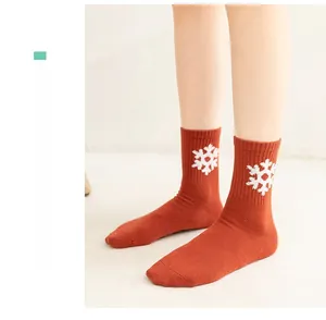 Close-up of bright orange crew socks with white snowflake patterns and ribbed cuffs
