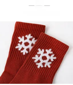 Detail view of brick red ribbed cotton socks featuring white knitted snowflake patterns