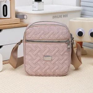 Detail view of pink quilted crossbody bag with multi-zipper layers and wide strap