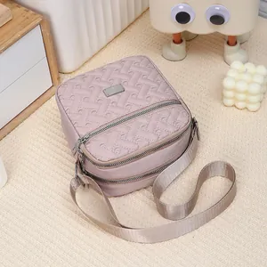Detail of multi-layer embroidered crossbody bag with silver zippers and wide nylon strap