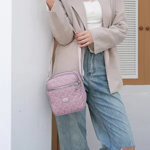 Close-up of lavender quilted crossbody bag with silver zipper and wide fabric strap
