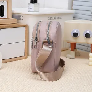 Detailed view of the small three-layer nylon crossbody phone bag with wide fabric strap