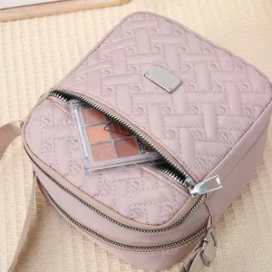 Detail of pink crossbody bag with heart embroidery showing makeup storage capacity