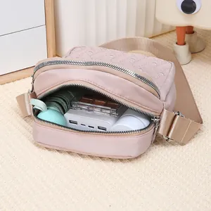 Detail view of light pink nylon crossbody bag with interior space for daily essentials
