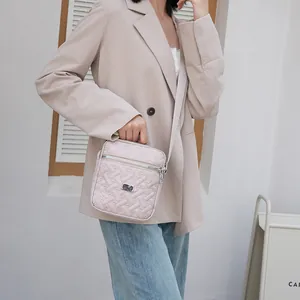 Detail of light pink quilted crossbody bag showing texture and silver hardware on model