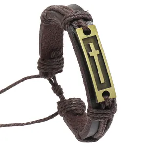 Detail of vintage braided leather bracelet with bronze cross pendant on white background